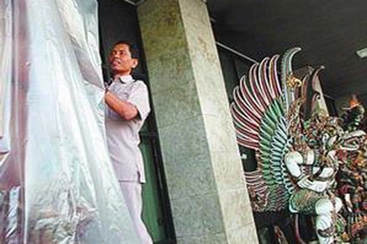 Karyawan Istana Kepresidenan, Jakarta, Kamis (11/1/2007), membungkus patung kayu berusia puluhan tahun dengan plastik seusai dirawat secara rutin. Ratusan patung Garuda Wisnu Kencana di Istana Kepresidenan Jakarta menanti dikirimkan ke semua istana kepresidenan di Indonesia. 