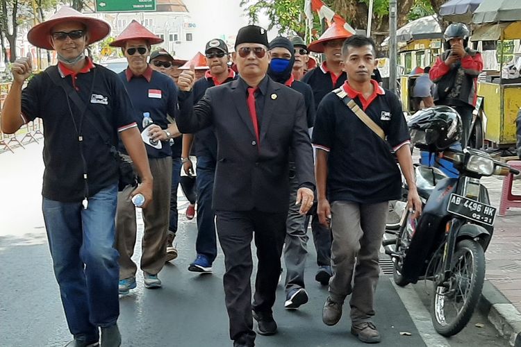 Mengenakan jas lengkap, anggota DPRD DIY Ispriyatun Katir Triatmojo berjalan kaki dari Kantor DPRD DIY menuju rumahnya di Kecamatan Banguntapan, Kabupaten Bantul.