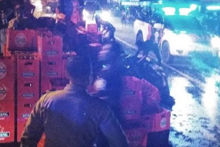 Polisi dibantu warga membersihkan botol bir yang tumpah memenuhi jalan 