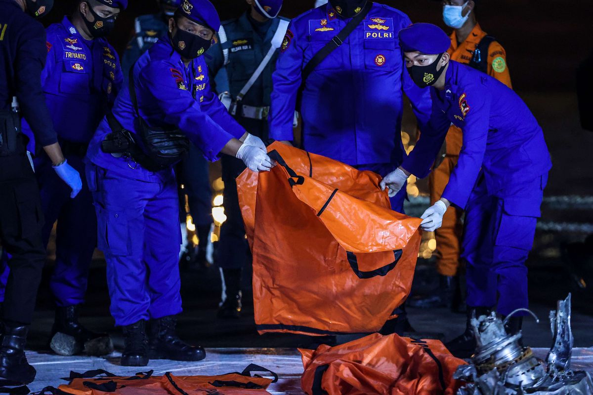 Anggota kepolisian mengangkat kantong jenazah berisi objek temuan dari lokasi jatuhnya pesawat Sriwijaya Air SJ 182 rute Jakarta-Pontianak pada hari ketujuh Operasi SAR pesawat tersebut di Dermaga JICT 2, Tanjung Priok, Jakarta Utara, Jumat (15/1/2021).