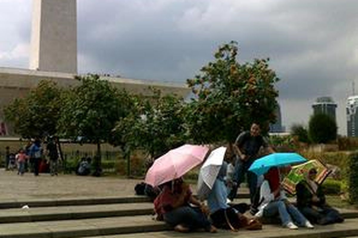Beberapa pengunjung Monas menikmati akhir pekan sambil duduk-duduk di pelataran Monas. Sebagai salah satu tujuan wisata di Jakarta, Monas memang tidak pernah sepi.