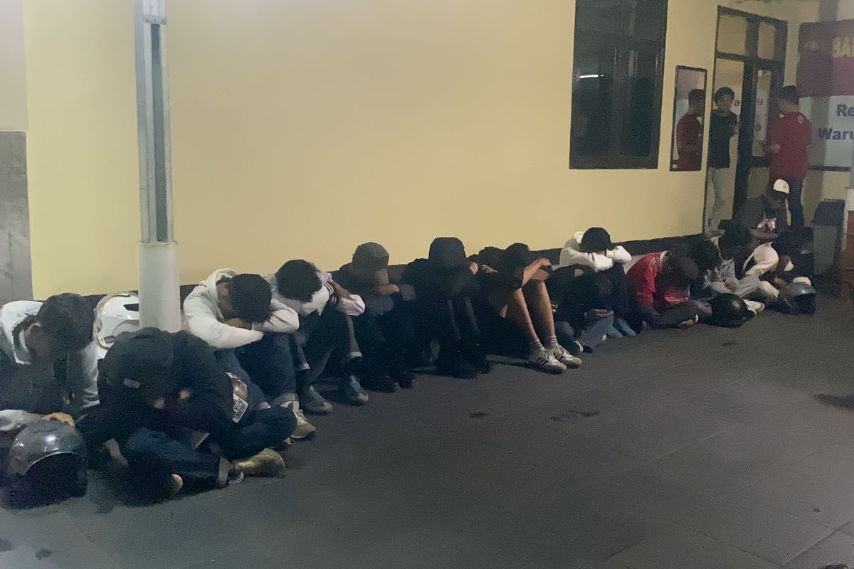 Sebanyak 13 orang supertor Persija Jakarta yang tengah berada di Polsek Warudoyong Kota Sukabumi tertunduk malu, mereka diamankan dari buntuk aksi pengrusakan pagar rumah milik warga di Jalan Pajagalan, Kota Sukabumi, Senin (23/9/2024). 