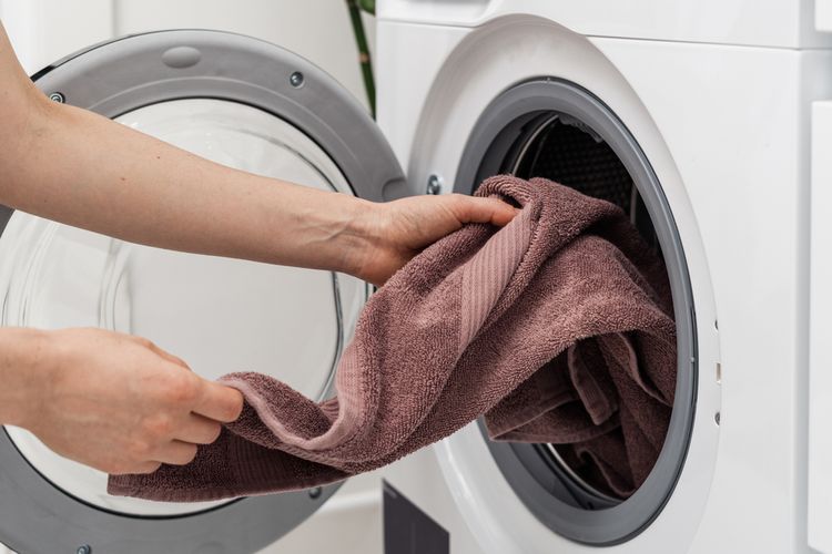 Ilustrasi mencuci handuk dengan mesin cuci.