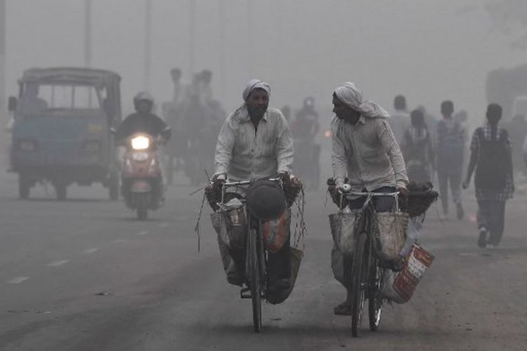 Suasana jalan di New Delhi yang diselimuti kabut tebal akibat polusi terparah, Selasa (7/11/2017). (AFP/Prakash Singh)