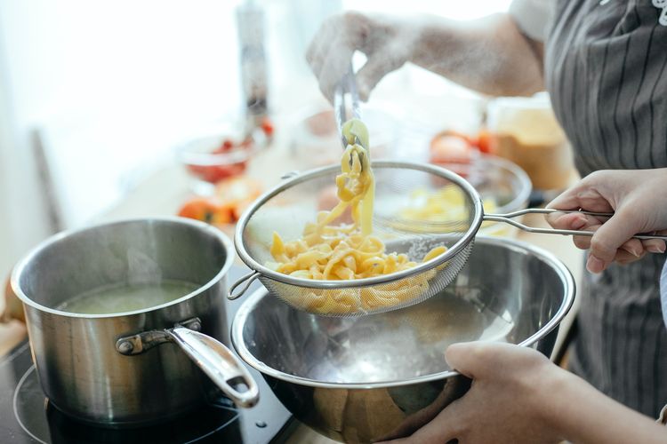 Ilustari orang yang sedang memasak mi. 