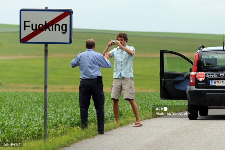 Dalam foto bertanggal 18 Juni 2008, dua turis tengah berfoto di depan papan penanda nama desa Fucking, sekitar 35 km di utara Salzburg, Austria. Mulai tahun depan, nama desa itu berubah menjadi Fugging setelah mereka tidak tahan dengan ejekan yang diterima di media sosial.