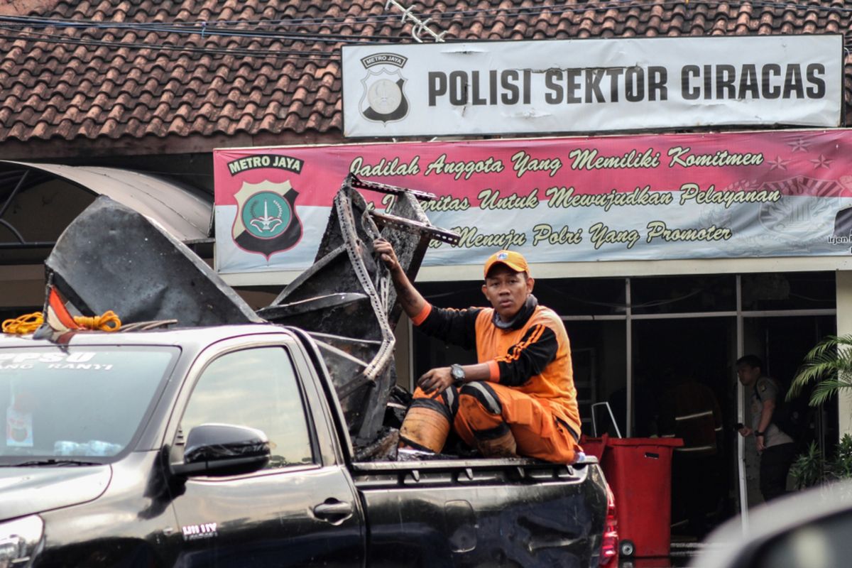 Petugas kebersihan mengangkut barang sisa perusakan dan pembakaran di Polsek Ciracas, Jakarta, Rabu (12/12/2018). Perusakakan dan pembakaran Polsek Ciracas yang dilakukan ratusan orang itu  terjadi pada Rabu dini hari (12/12/2018), yang dipicu ketidakpuasan atas penanganan kasus pemukulan seorang anggota TNI.