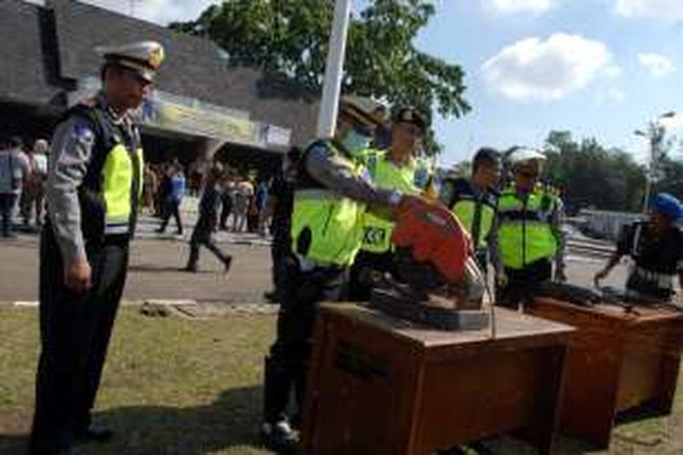 Petugas kepolisian Polres Sukabumi Kota memotong knalpot bising usai apel gelar pasukan Operasi Ramadniya di lapang Merdeka, Sukabumi, jawa Barat, Kamis (30/6/2016). 