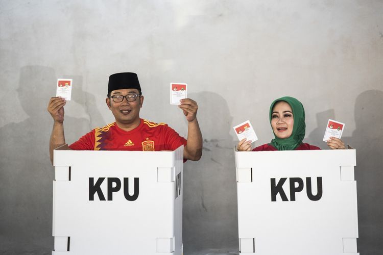 Calon Gubernur Jawa Barat nomor urut satu Ridwan Kamil (kiri) bersama istri Atalia Praratya (kanan) menunjukkan surat suara saat menggunakan hak pilih di TPS 21 Bandung, Jawa Barat, Rabu (27/6/2018). Pilgub Jabar diikuti empat pasang cagub dan cawagub dengan jumlah daftar pemilih tetap (DPT) sebanyak 31.735.133 pemilih. 