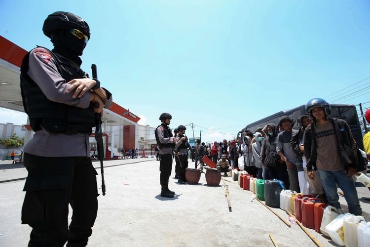 Polisi menjaga warga yang antre membeli bahan bakar minyak di salah satu SPBU di Kota Palu, Sulawesi Tengah, pasca gempa dan tsunami, Rabu (3/10/2018). Hingga Hari ini pasokan BBM dari Pertamina di Palu berangsur normal.