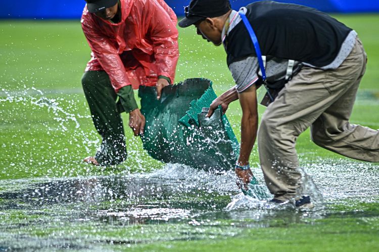 Momen saat petugas lapangan Stadion Gelora Bandung Lautan Api (GBLA) menyisikan air yang menggenang dalam hujan deras mewarnai laga pekan kelima Super League 2025-2026 antara Persib Bandung vs Persebaya Surabaya, Jumat (12/9/2025). 