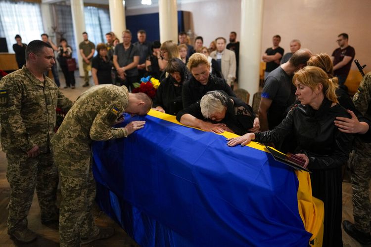 Istri (kanan), dan ibu (kedua dari kanan) dari Kolonel Angkatan Darat Ukraina Oleksander Makhachek, berkabung atas peti matinya selama upacara pemakaman di Zhytomyr, Ukraina, Jumat, 3 Juni 2022. 