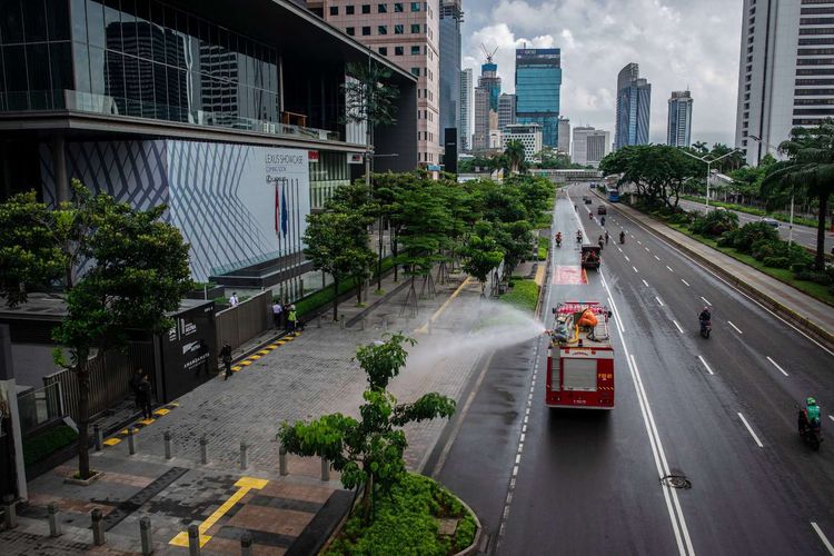 Petugas Damkar menyemprotkan cairan disinfektan di kawasan Jalan Sudirman, Jakarta, Minggu (22/3/2020). Pemprov DKI Jakarta melakukan penyemprotan fasilitas umum menggunakan cairan disinfektan di lima wilayah DKI Jakarta untuk mencegah penyebaran virus Corona atau COVID-19.