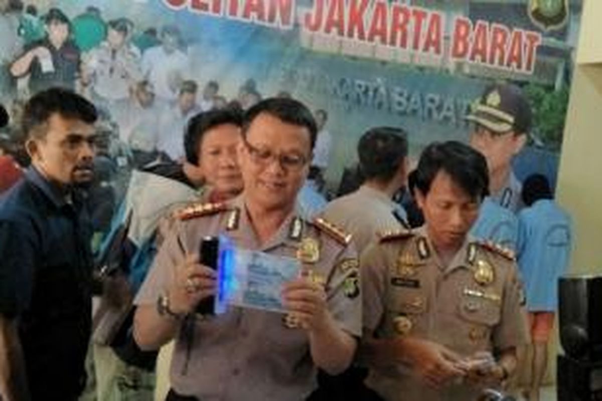 Kapolres Metro Jakarta Barat Komisaris Besar Rudy Heriyanto Adi Nugroho (tengah) menunjukkan perbedaan uang asli dan uang palsu yang diproduksi Lucky dan teman-temannya, Jumat (25/9/2015).
