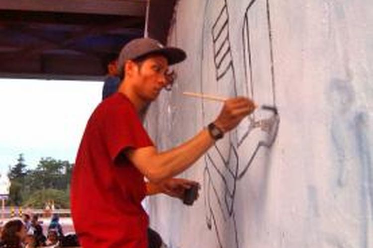 Salah satu seniman street art saat menuangkan karyanya di dinding ktetek kewek dengan tema 