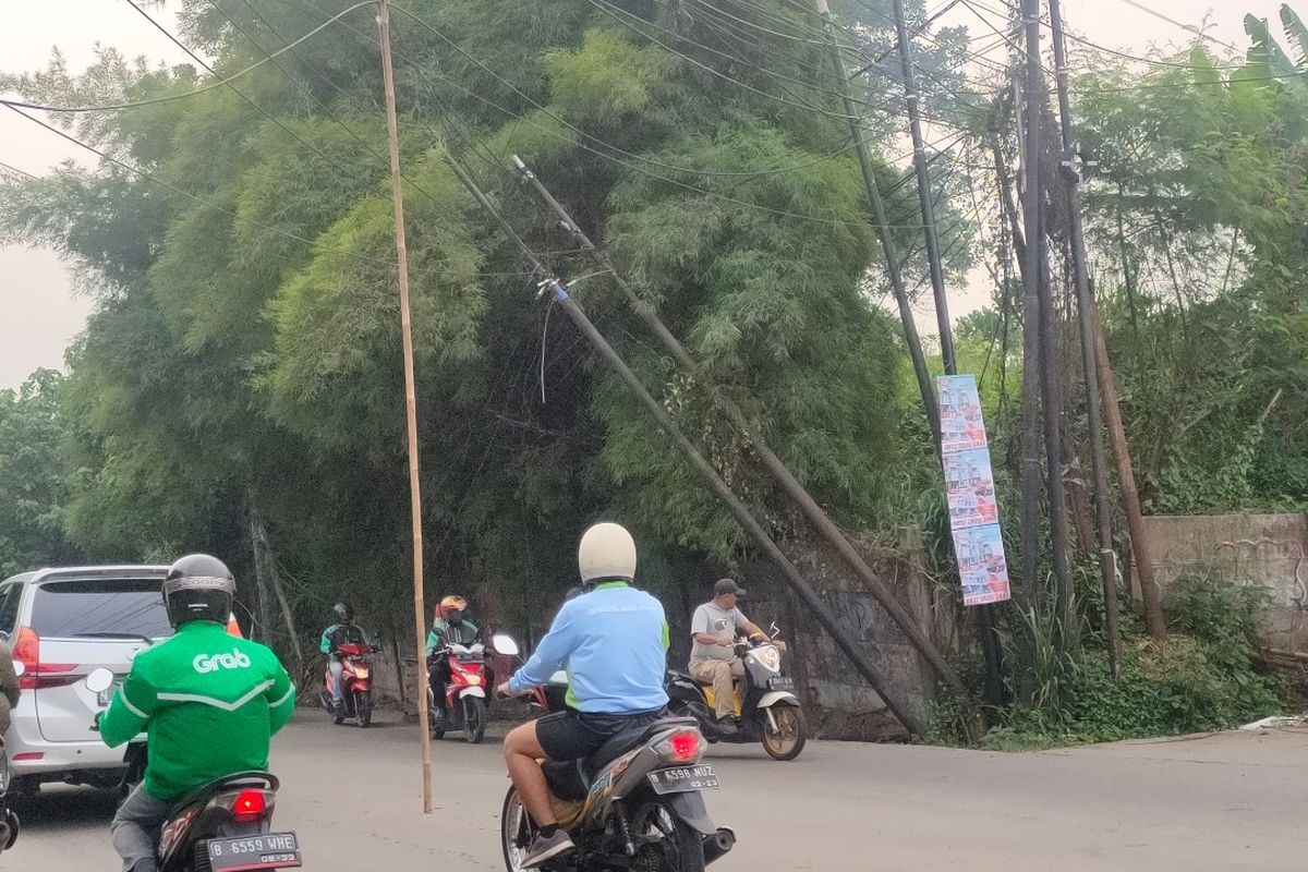 Tiang listrik roboh dan miring sebabkan kabel kabel menjuntai di Jalan Raya Siliwangi, Pamulang, Tangerang Selatan, Selasa (30/3/2021).