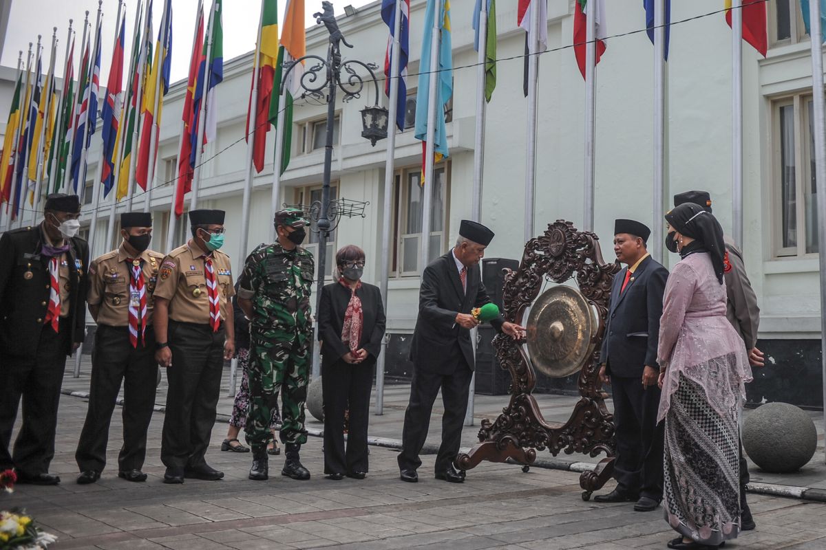Dirjen Informasi dan Diplomasi Publik Kementerian Luar Negeri Teguh Wardoyo (tengah) didampingi Wakil Gubernur Jawa Barat Uu Ruzhanul Ulum memukul gong sebagai tanda pembukaan rangkaian peringatan 67 tahun Konferensi Asia Afrika (KAA) saat upacara pengibaran bendera peserta KAA di Jalan Sukarno, Bandung, Jawa Barat, Senin (18/4/2022).