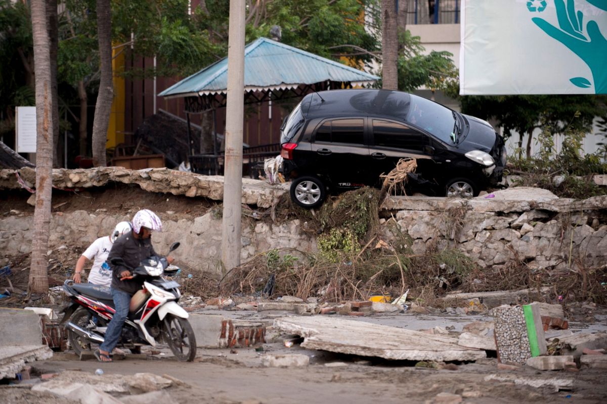 Seorang pria berusaha mengendarai sepeda motornya melalui lumpur di Pal, Sulawesi Tengah, Sabtu (29/9/2018), setelah gempa kuat dan tsunami melanda daerah tersebut. Hampir 400 orang tewas akibat gempa dan tsunami di Sulawesi Tengah, Jumat (28/9/2018).