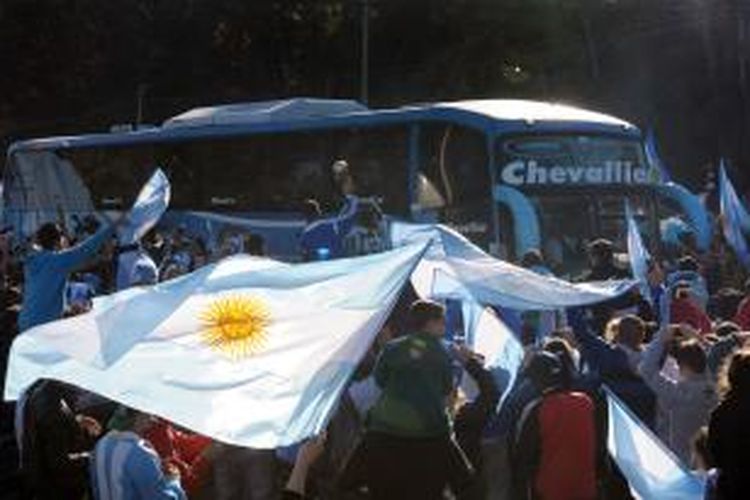 Suporter sepak bola Argentina mengerumuni bus yang membawa para pemain Argentina ke bandara Ezeiza untuk terbang ke Brasil, Senin (9/6/2014).