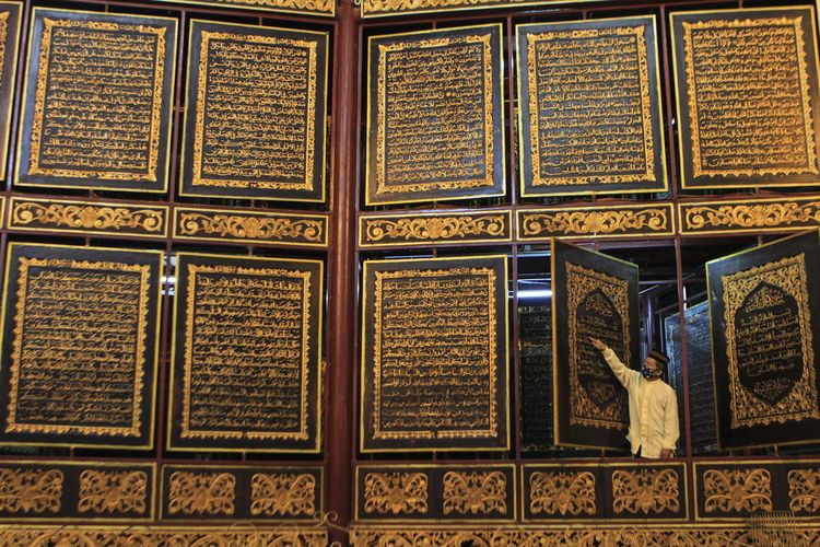 Syarkoni, pemandu wisata Al Quran Al Akbar memperlihatkan ukiran ayat suci Al Quran yang dibuat di atas kepingan kayu tembesu. Wisata religi ini menjadi tempat favorit ketika berkunjung ke Palembang, Sumatera Selatan,Minggu (10/4/2022).