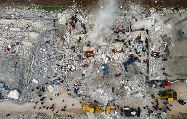 Pemandangan dari udara ini menunjukkan penduduk yang dibantu oleh buldoser, mencari korban dan penyintas di puing-puing bangunan yang runtuh, menyusul gempa Turkiye di kota Sarmada, pedesaan provinsi Idlib, Suriah barat laut, 6 Februari 2023 dini hari. Gempa berkekuatan besar melanda Turkiye dan Suriah pada 6 Februari, menewaskan ribuan orang saat mereka tidur, meratakan bangunan, dan guncangannya terasa hingga pulau Siprus dan Mesir.