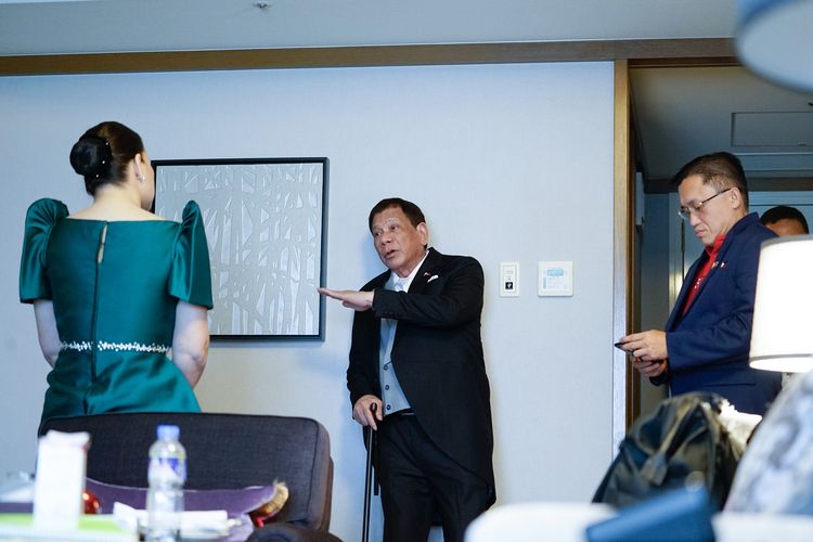 Foto yang dirilis Divisi Media Kepresidenan Filipina (PPD) pada 22 Oktober 2019 menunjukkan Presiden Rodrigo Duterte berjalan menggunakan tongkat sembari berbicara dengan putrinya, Sara Duterte-Carpio. Duterte dilaporkan harus mempersingkat kunjungannya ke Jepang karena menderita sakit tak tertahankan.