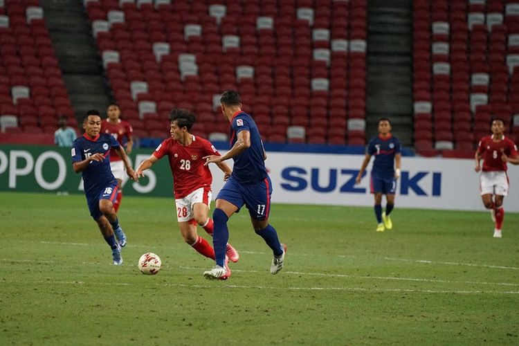 Indonesia vs Singapura: Bek timnas Indonesia Alfeandra Dewangga dalam bayangan para pemain Singapura pada laga semifinal Piala AFF 2020 di Stadion Nasional, Sabtu (25/12/2021).