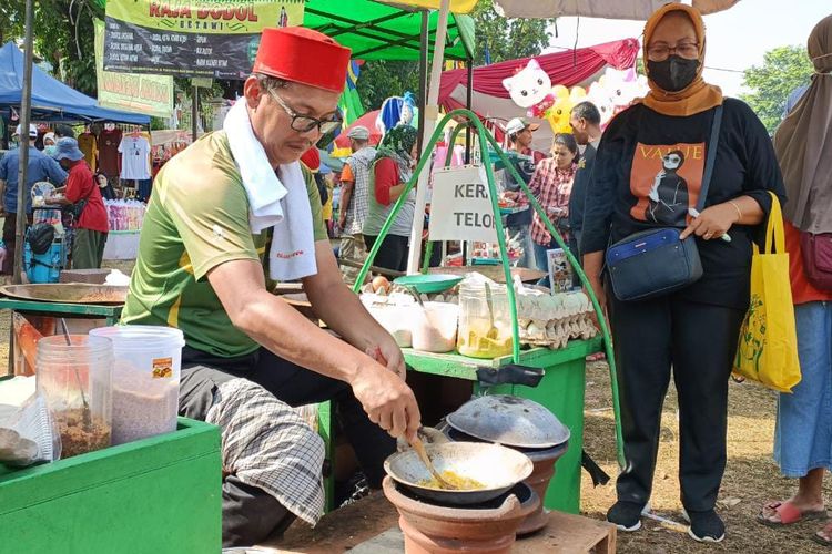 Seorang penjual kerak telor yang sedang melayani pembelinya di Festival Condet yang digelar di Lapangan Sepak Bola Gedong Rindam Jaya, Jalan Raya Condet, Jakarta Timur. Selain kuliner khas budaya Betawi, berbagai pertunjukkan seperti pertunjukkan musik, pawai budaya, marawis, hingga tanjidor turut memeriahkan acara yang digelar selama dua hari tersebut.