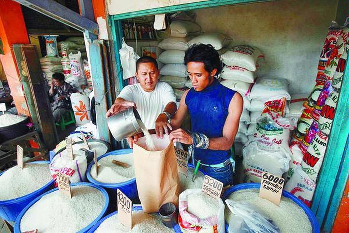 Robby (kiri), pedagang beras, dan Agus memasukkan beras ke dalam kantong kertas di Pasar Tradisional Ciplak, Jakarta Timur, Rabu (14/5). Rencana pemerintah akan menaikkan harga BBM bersubsidi pada awal Juni disambut dengan kenaikan harga beberapa bahan pokok, seperti beras.  