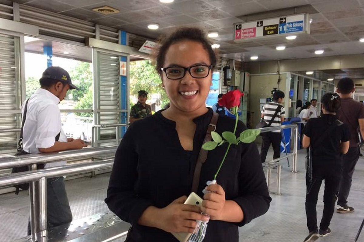 Salah satu penumpang transjakarta, Eda Tukan (24), menerima bunga mawar yang diberikan petugas di halte transjakarta Kampung Melayu, Jakarta Timur, Senin (29/5/2017). Halte itu kembali beroperasi setelah sempat ditutup akibat ledakan bom pada Rabu lalu.