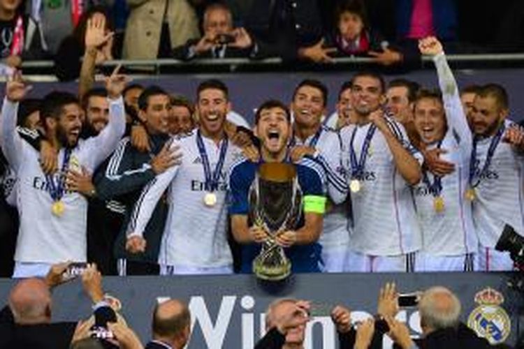 Kiper Real Madrid, Iker Casillas, mengangkat trofi Piala Super Eropa setelah mereka menang 2-0 atas Sevilla dalam laga di Cardiff, Selasa (12/8/2014).