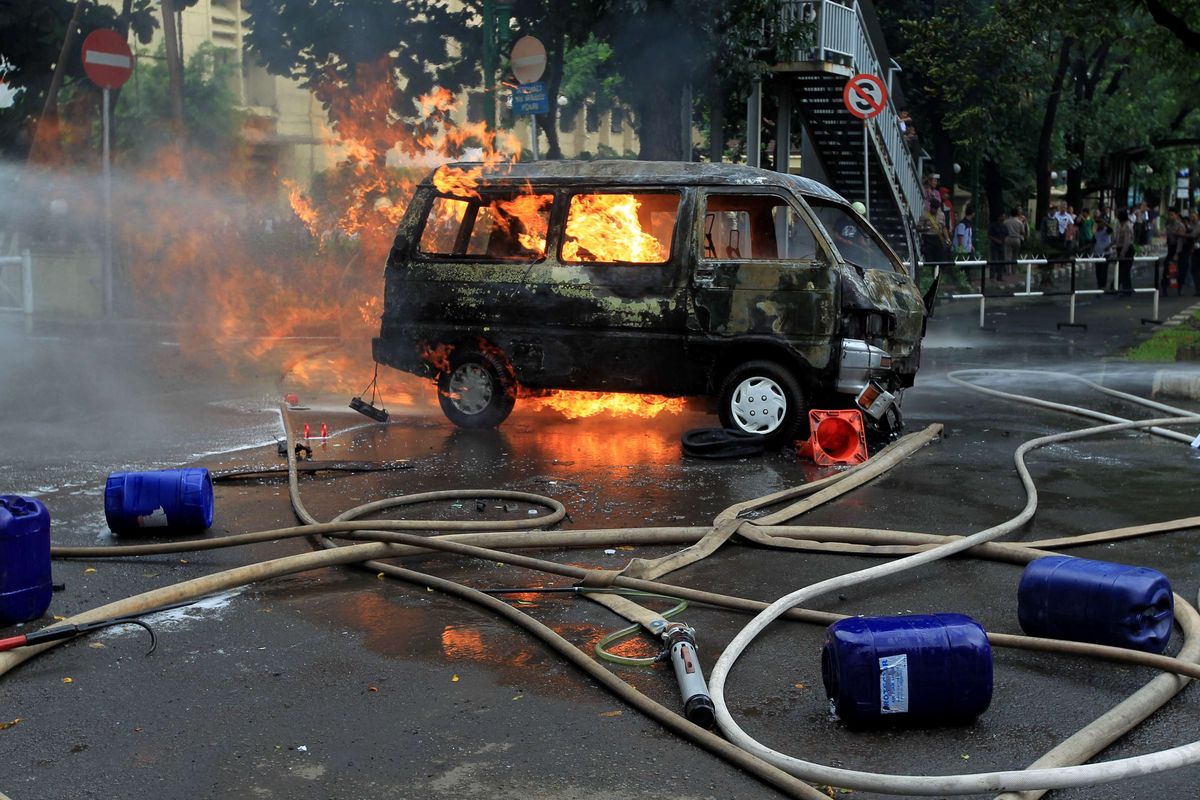 Petugas berusaha memadamkan mobil Daihatsu Zebra B2791AJ yang terbakar di Jalan Trunojoyo, samping Mabes Polri, Kebayoran Baru, Jakarta, Rabu (4/2/2015). Mobil itu membawa lima tangki berisi ratusan liter bahan bakar minyak.  KOMPAS IMAGES/KRISTIANTO PURNOMO
