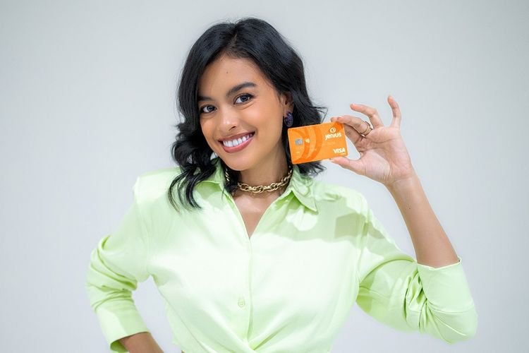 Eva Celia memegang Kartu Debit Jenius m-Card berwarna oranye.