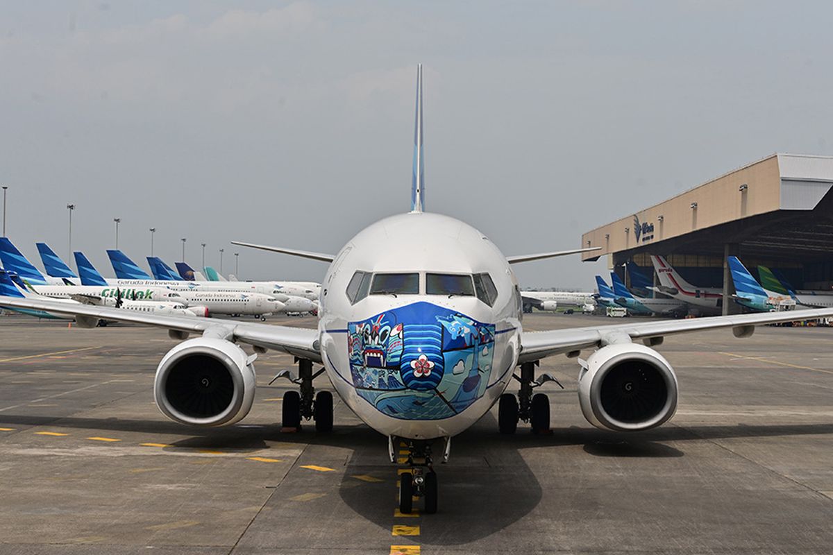 Pesawat Garuda Indonesia Boeing 373-800 NG dengan desain masker di bagian depan pesawat, saat diparkir di lapangan udara di Tangerang, Banten, Senin (12/10/2020). Pemasangan ''masker'' di pesawat tersebut digelar untuk mendukung kampanye Gerakan 'Ayo Pakai Masker' dalam rangka penanggulangan pandemi Covid-19.