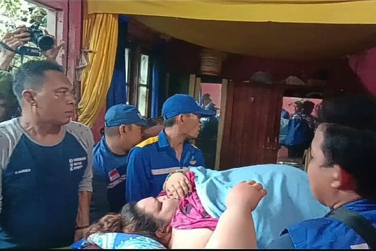 Sekitar 20 anggota tim sukarelawan mengangkat Titi Wati menuju ke dalam rumah, Senin (21/1/2019). 