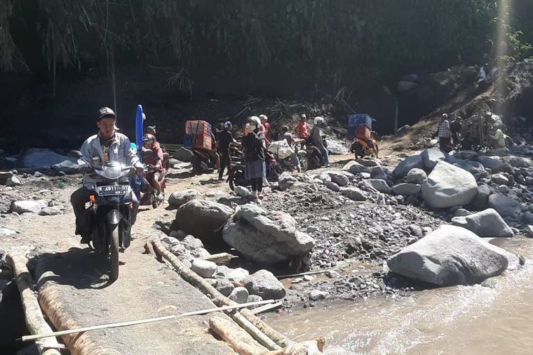 Warga melintasi jembatan darurat yang menghubungkan Malang dan Lumajang, Selasa (11/7/2023).