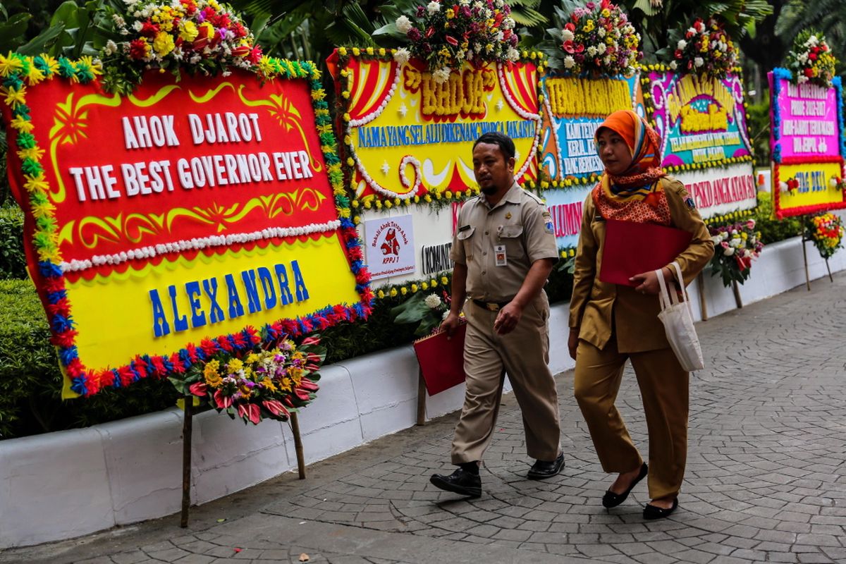 Warga melintas di antara karangan bunga yang ditujukan untuk Basuki Tjahaja Purnama atau Ahok dan Djarot Saiful Hidayat di kompleks Balai Kota DKI Jakarta, Senin (9/10/2017). Karangan bunga tersebut berisi ucapan terima kasih dari warga atas kepemimpinan Basuki dan Djarot selama berpasangan menjadi gubernur dan wakil gubernur DKI Jakarta.