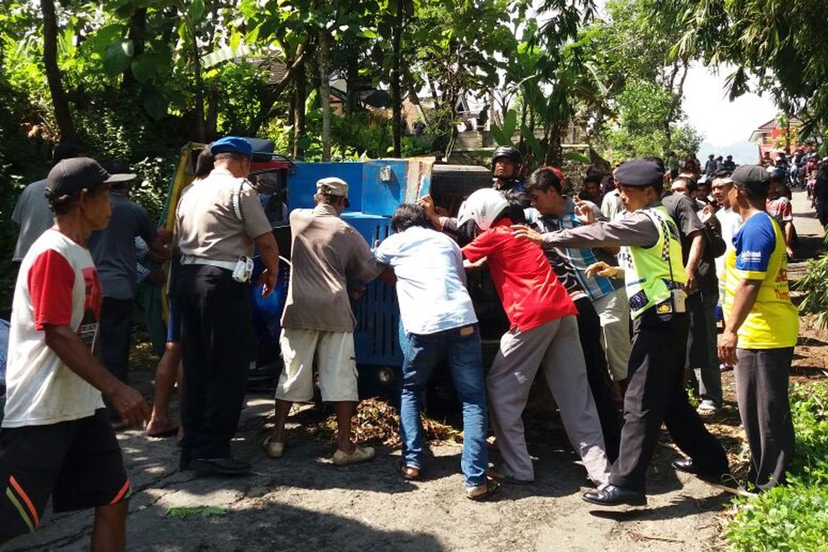 EVAKUASI -Warga membantu mengevakuasi kereta kelinci yang terguling di ruas jalan Dukuh Gembes, Desa Slahung, Kecamatan Slahung, Kabupaten Ponorogo, Rabu ( 1/3/2017).