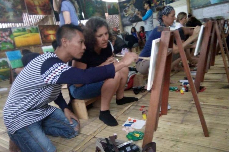 Salah seorang seniman lukis Jelekong sedang memberi bimbingan lukis pada wisatawan Perancis.