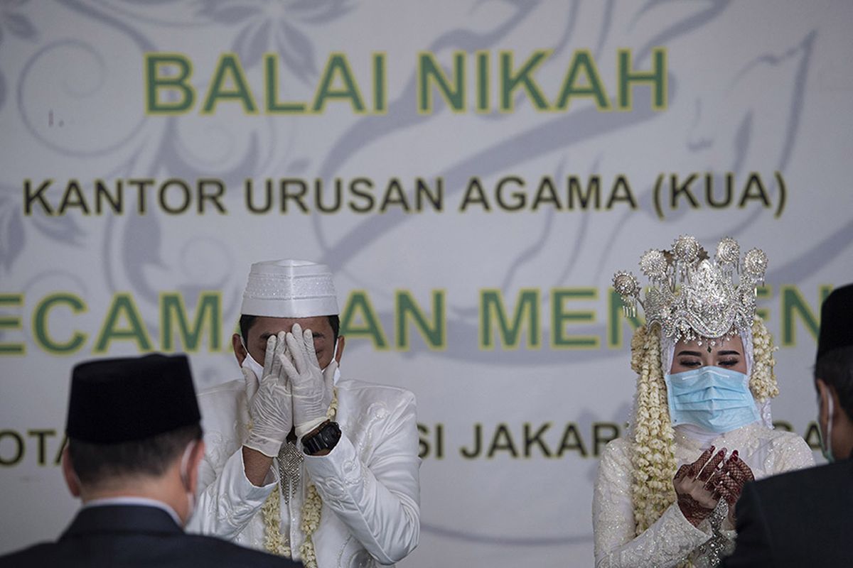 Pasangan pengantin Novi Herdjanto (kedua kiri) dan Mellawati Isnoer memanjatkan doa dalam prosesi akad nikah di Kantor Urusan Agama Kecamatan Menteng, Jakarta Pusat, Sabtu (11/4/2020). Selama penerapan Pembatasan Sosial Berskala Besar (PSBB) Pemprov DKI Jakarta hanya memperbolehkan akad nikah di Kantor Urusan Agama dan melarang adanya resepsi pernikahan.