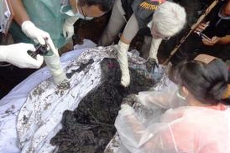 Petugas membuka bungkusan kain berisi jenazah, yang diduga Iin (20), warga Desa Yosorati, Kecamatan Sumberbaru, Jember Jawa Timur, yang dibunuh ibu kandungnya sendiri, Sl (38). Jasad tersebut ditemukan setelah dilakukan penggalian septic tank, Kamis ((7/8/2014).