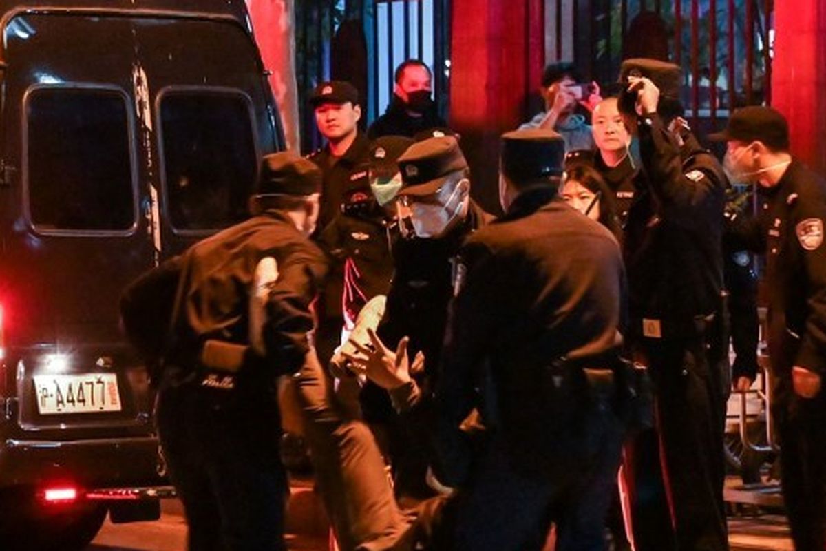 Seorang pria ditangkap saat orang-orang berkumpul di sebuah jalan di Shanghai pada 27 November 2022, di mana protes terhadap kebijakan nol-Covid China terjadi pada malam sebelumnya menyusul kebakaran mematikan di Urumqi, ibu kota wilayah Xinjiang. 