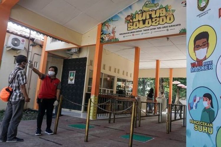 Petugas melakukan pemeriksaan suhu tubuh warga yang akan memasuki Taman Satwa Taru Jurug (TSTJ) di Solo, Jawa Tengah. Kebun binatang TSTJ dibuka kembali pada 19 Juni 2020 dan menerapkan aturan normal baru sesuai protokol kesehatan yaitu salah satunya dengan pembatasan jumlah kunjungan wisatawan. 