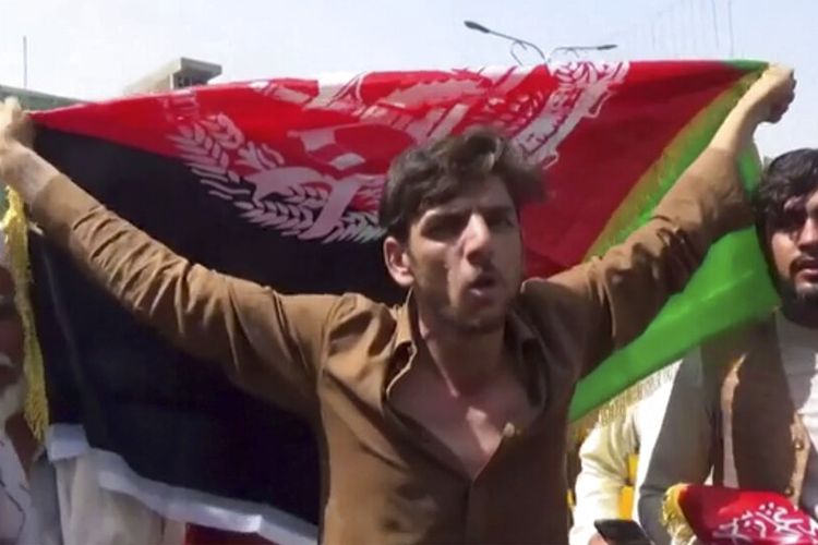Seorang pria memegang bendera Afghanistan selama protes di Jalalabad pada hari Rabu, 18 Agustus 2021.