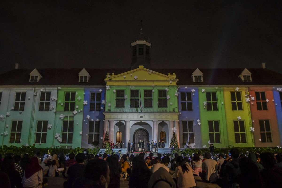 Warga menyaksikan video mapping bernuansa Natal yang ditampilkan saat acara 'Christmas in Jakarta' di Taman Museum Fatahillah, Kota Tua, Jakarta, Minggu (19/12/2021). Pemerintah Provinsi DKI Jakarta menggelar acara 'Christmas in Jakarta' dengan tema Harmony with History dalam rangka menyambut perayaan Natal 2021.