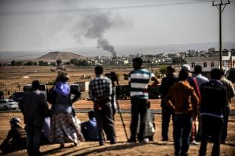 Sejumlah warga dari pintu perbatasan Mursitpinar di kota Suruc, provinsi Sanliurfa, Turki, memandang asap hitam membubung dari kota Kobani, Suriah yang sedang diperebutkan pasukan ISIS dan Kurdi.