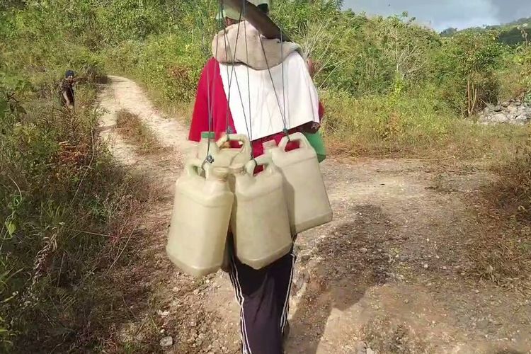 Warga Dusun Katolemando berjalan kaki menyusuri jalan setapak di bekas galian tambang aspal di Kecamatan Sampolawa, Kabupaten Buton Selatan, Sulawesi Tenggara