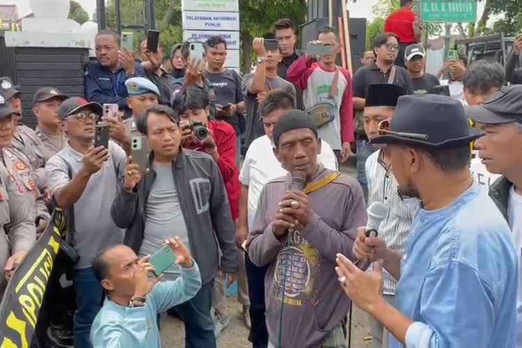 Pak Asi (54) saat memegang pengeras suara dan berorasi di depan kantor Kejari Sumenep. 