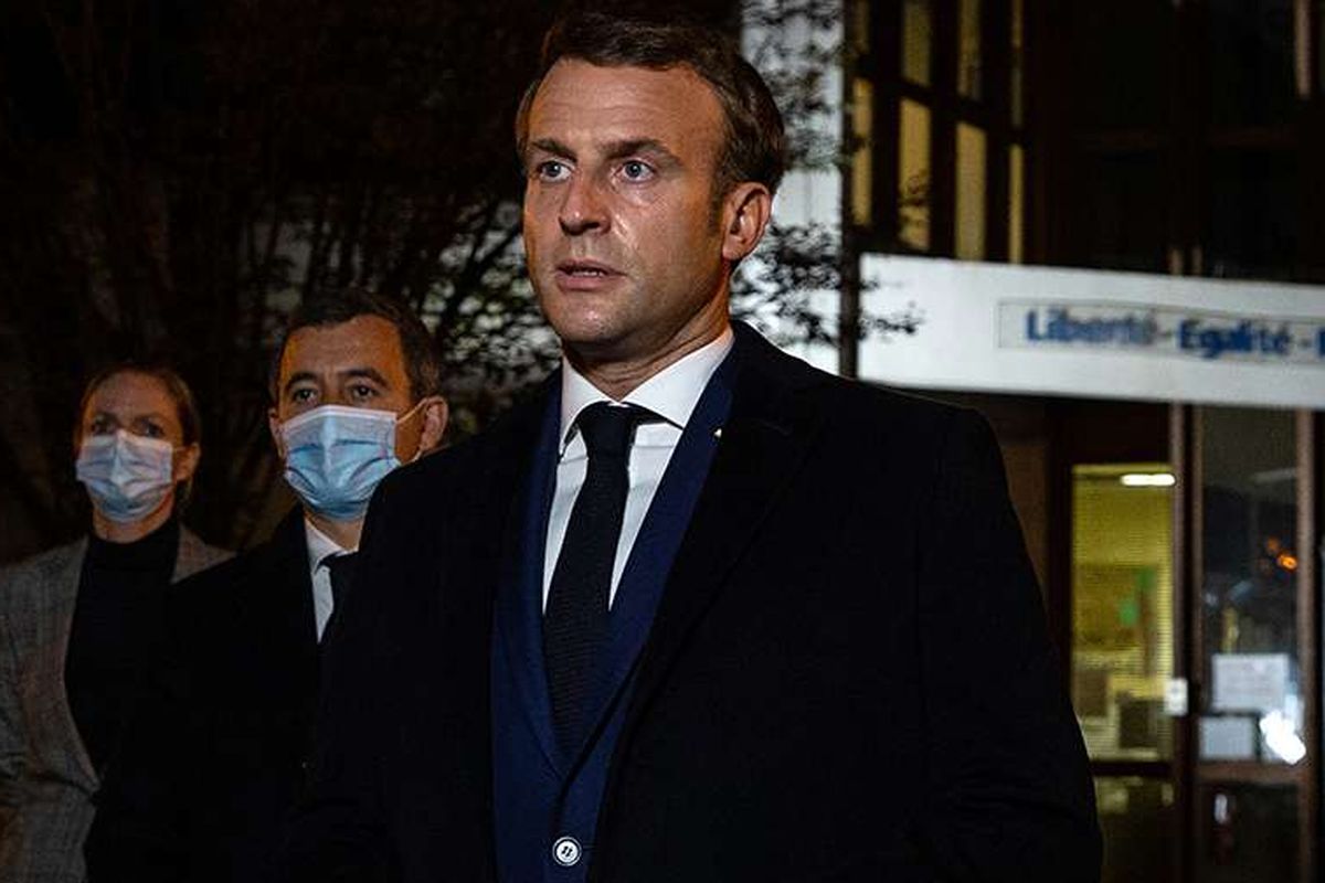 French President Emmanuel Macron (right) talks to the press in front of the high school in Paris Conflans Saint-Honorine where teacher Samuel Paty taught. A Muslim extremist beheaded Paty for showing his students cartoons from Charlie Hebdo mocking the Prophet Muhammad