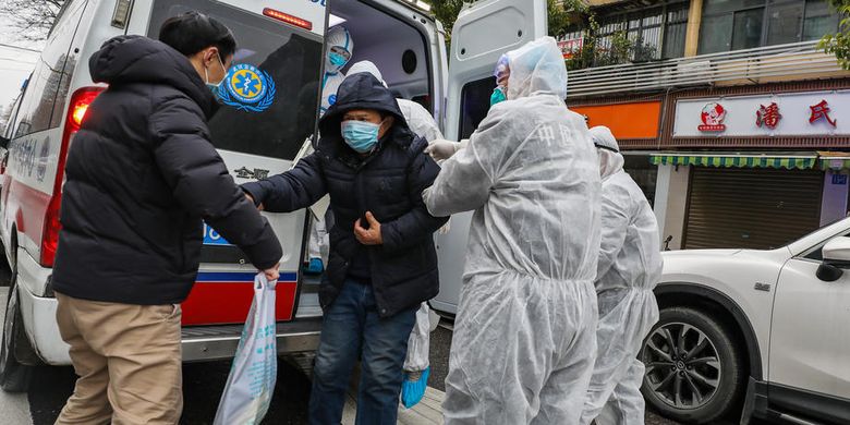 Petugas medis yang mengenakan pakaian pelindung membantu pasien turun dari ambulans di luar rumah sakit di Wuhan, Hubei, China, pada 26 Januari 2020. Penyebaran virus corona sejak Desember 2019 sudah membunuh lebih dari 300 orang di China.